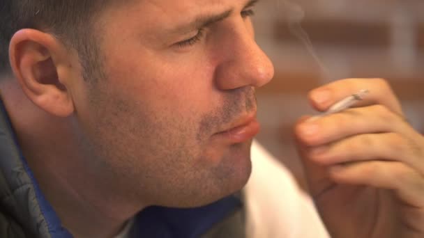 Молодой человек курит сигарету — стоковое видео
