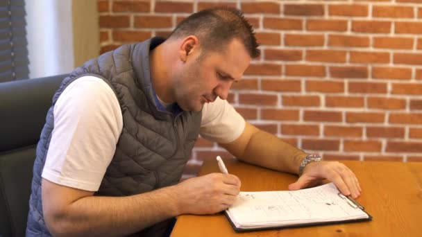 Young man working in modern office and writing note — Stock Video