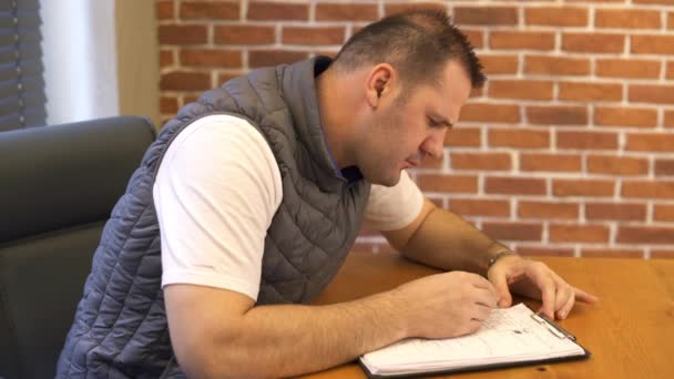 Jovem trabalhando em escritório moderno e escrevendo nota — Vídeo de Stock