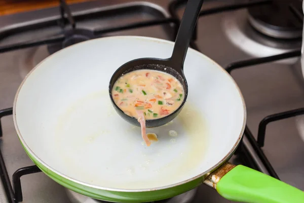 Разлить омлет на сковородку — стоковое фото