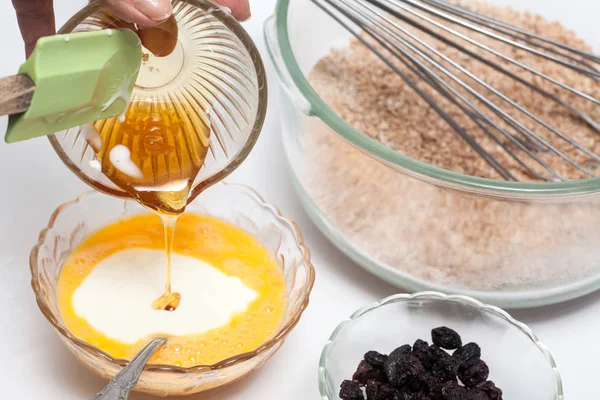 Προσθέτοντας μέλι στο μίγμα για να προετοιμάσει αναπόσπαστο σιτάρι muffins πίτουρου — Φωτογραφία Αρχείου