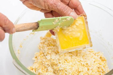 Adding melted butter to prepare sweet corn bread clipart