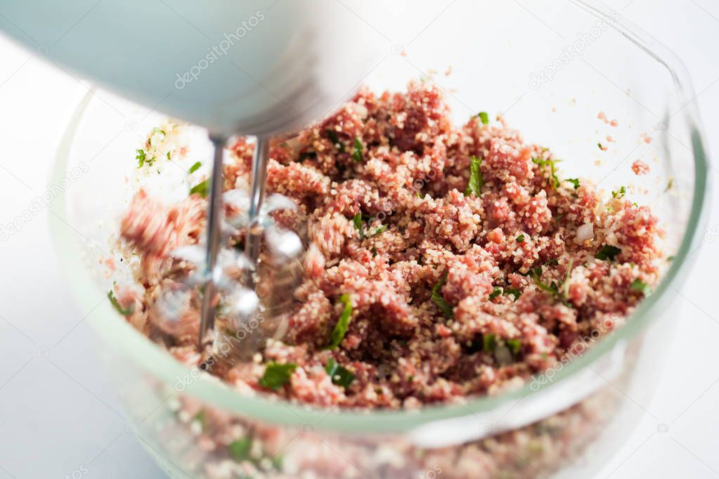 Mixing the ingredients to prepare kibbeh into a bowl