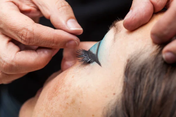 Maquillaje artista aplicando las pestañas falsas a un wo —  Fotos de Stock