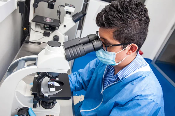 Cientista masculino olhando para lâminas sob o microscópio — Fotografia de Stock