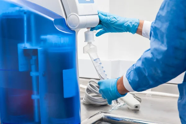 Scientist filling a graduated cylinder with distilled water — Stock Photo, Image