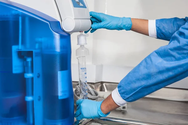Cientista enchendo um cilindro graduado com água destilada — Fotografia de Stock