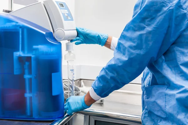 Scientist filling a graduated cylinder with distilled water — Stock Photo, Image