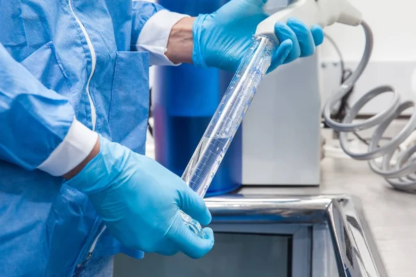 Cientista enchendo um cilindro graduado com água destilada — Fotografia de Stock