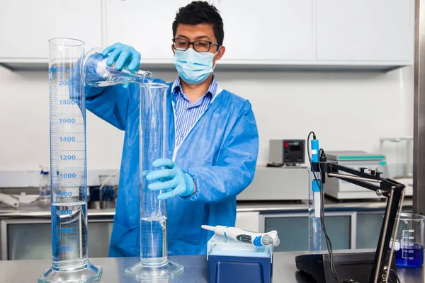 Jovem cientista do sexo masculino que trabalha em laboratório vestido de azul — Fotografia de Stock