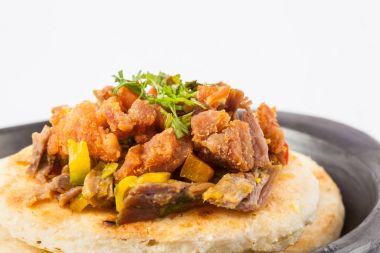 Kolombiyalı arepa parçalanmış sığır eti ve domuz eti kabuğu ile tepesinde