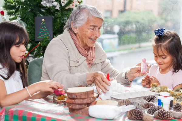 Abuela enseñando a sus nietas a hacer artesanías navideñas de Natividad - Familia real — Foto de Stock