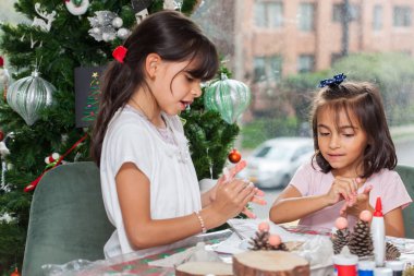 İki küçük kız kardeş Noel 'de evde el sanatları yaparken eğleniyorlar.