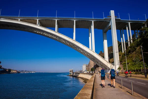 Turistas e habitantes locais desfrutam de um belo dia de primavera junto ao rio Douro e da Ponte Arrabida na Cidade do Porto, em Portugal — Fotografia de Stock