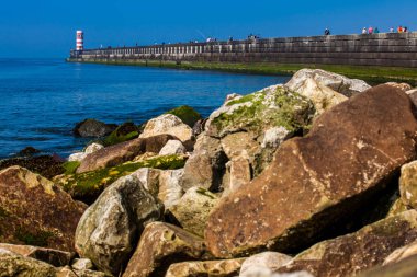İnsanlar Farolins da Barra do Douro 'da güneşli bir bahar gününün tadını çıkarıyorlar. Douro nehrinin ağzının yanındaki güzel Porto sahilinde.
