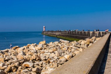 İnsanlar Farolins da Barra do Douro 'da güneşli bir bahar gününün tadını çıkarıyorlar. Douro nehrinin ağzının yanındaki güzel Porto sahilinde.