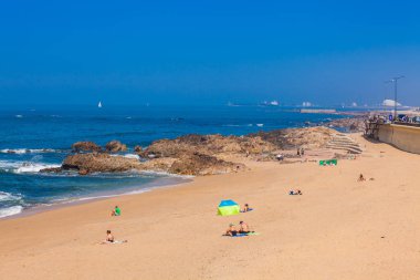İnsanlar Porto şehri kıyısındaki güzel plajlarda güneşli bir bahar gününün tadını çıkarıyor.