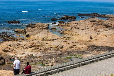 İnsanlar Porto şehri kıyı şeridi boyunca gezinti alanında güzel bir bahar gününün tadını çıkarıyorlar.