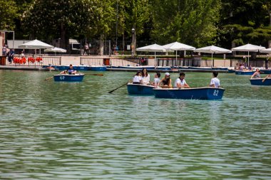 MADRID, SPAIN - MAY, 2018: Tourists and locals enjoying a beautiful spring day sailing at the Retiro Park pond