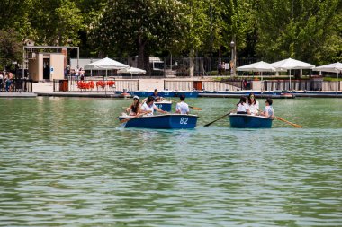MADRID, SPAIN - MAY, 2018: Tourists and locals enjoying a beautiful spring day sailing at the Retiro Park pond