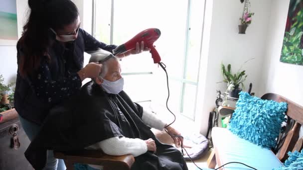 Mujer mayor recibiendo un corte de pelo en casa durante la pandemia de Covid-19 con mascarilla facial — Vídeo de stock