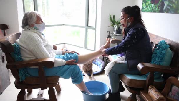 Wanita senior mendapatkan pedikur di rumah selama pandemi Covid-19 mengenakan topeng wajah — Stok Video