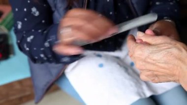 Covid-19 salgını sırasında evde manikür yaptırırken yaşlı kadın elini kapat.