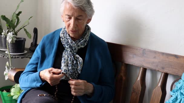 Старша жінка сама вдома молиться Святому Розареві — стокове відео