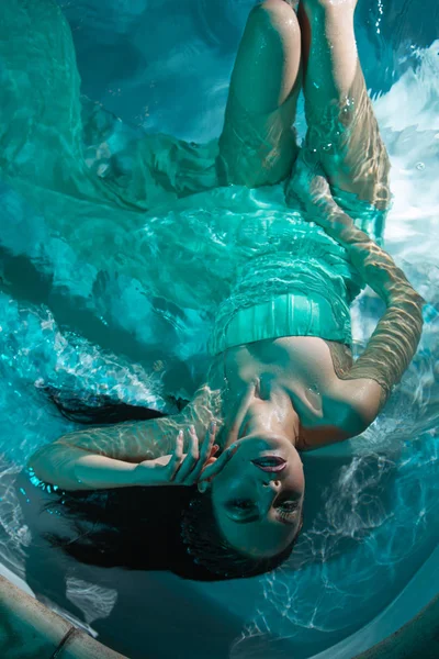 Beautiful girl in a dress dives under the water — Stock Photo, Image