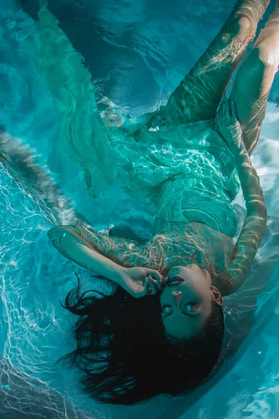 Beautiful girl in a dress dives under the water — Stock Photo, Image