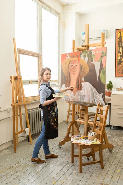 young artist paints a picture with oil in the Studio