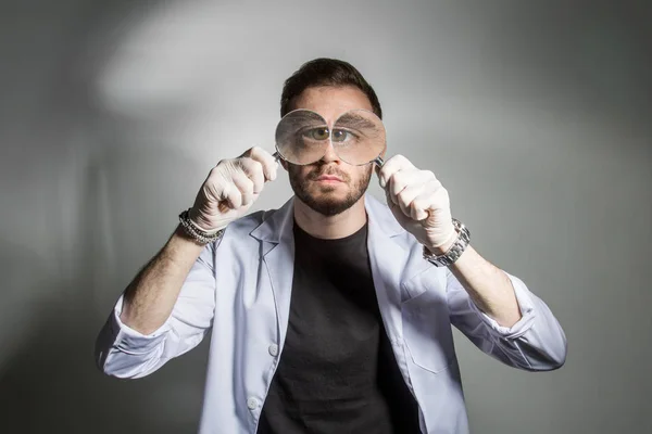 Riesige Augen eines Wissenschaftlers mit einer Lupe — Stockfoto