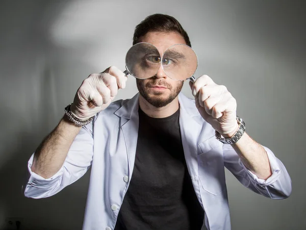 Riesige Augen eines Wissenschaftlers mit einer Lupe — Stockfoto