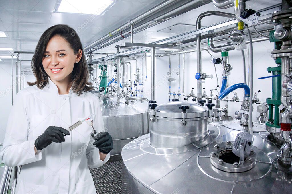 Scientist, researcher, microbiologist with a vaccine in a syringe against the background of drug production. Concept production of a vaccine during the covid-19 pandemic