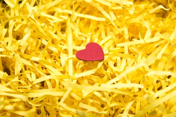 Желтый упаковочный материал и красная модель сердца — стоковое фото