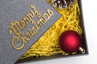 Neşeli Noel metin ve topu, çam kozalağı siyah hediye kutusunda sarı ambalaj malzemesi ile