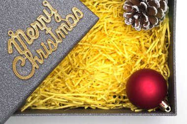 Neşeli Noel metin ve topu, çam kozalağı siyah hediye kutusunda sarı ambalaj malzemesi ile