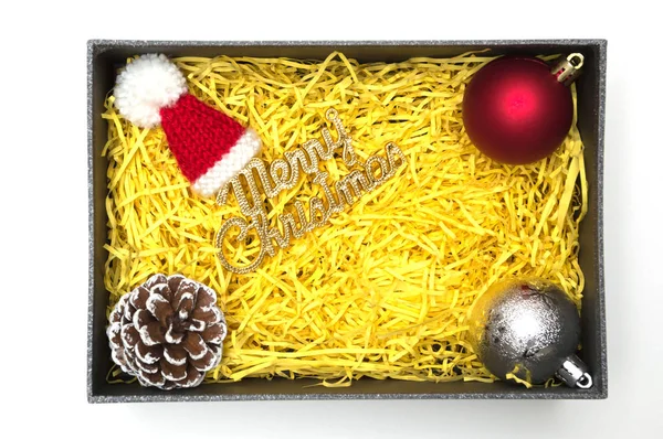 Neşeli Noel metin ve kürk şapka, topu, çam kozalağı siyah hediye kutusunda sarı ambalaj malzemesi ile