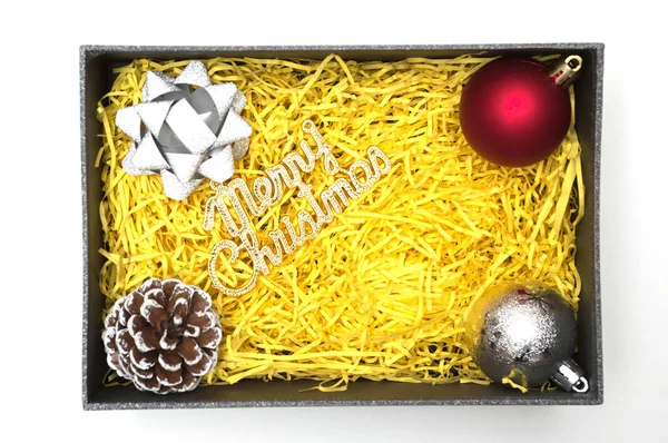 Neşeli Noel metin ve şerit, topu, çam kozalağı siyah hediye kutusunda sarı ambalaj malzemesi ile