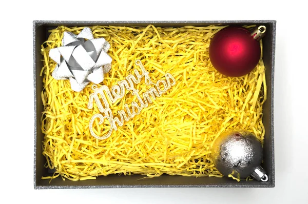 Frohe Weihnachten Text und Band, Kugel in schwarzer Geschenkbox mit gelbem Verpackungsmaterial — Stockfoto