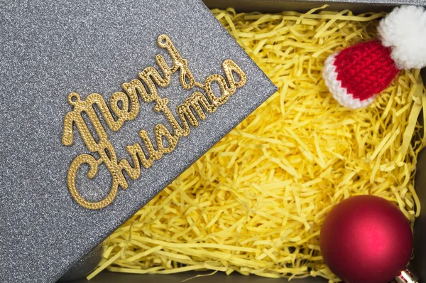 Neşeli Noel metin ve kürk şapka, top sarı ambalaj malzemesi ile siyah hediye kutusunda