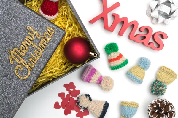 Joyeux Noël et Noël texte, chapeau de fourrure, boule, ruban, cône de pin, coeur en boîte cadeau noire avec matériau d'emballage jaune — Photo