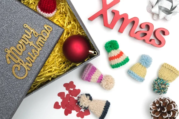 Frohe Weihnachten und Weihnachten Text, Pelzmütze, Ball, Band, Tannenzapfen, Herz in schwarzer Geschenkbox mit gelbem Verpackungsmaterial — Stockfoto