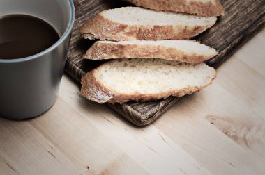 Kahve ile ahşap plaka üzerinde baget ekmek dilimlenmiş