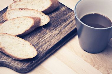 Kahve ile ahşap plaka üzerinde baget ekmek dilimlenmiş