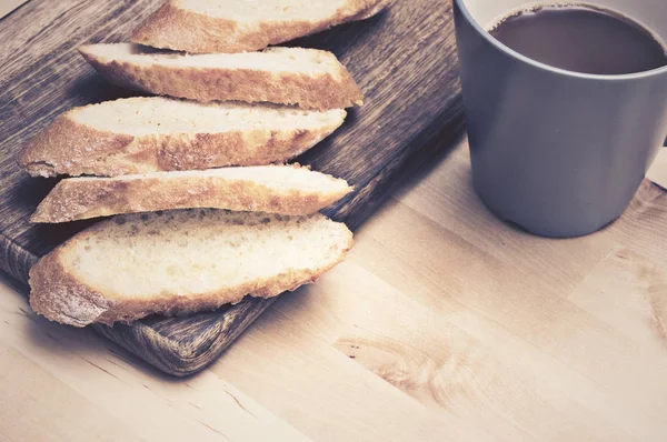 Pão de baguete fatiado em chapa de madeira com café — Fotografia de Stock