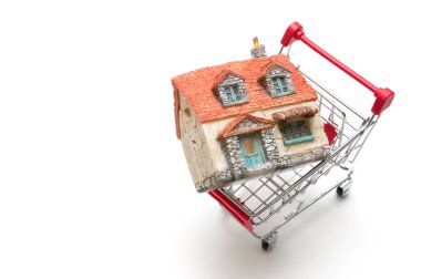 Minyatür ev ve beyaz arka plan üzerinde alışveriş sepeti: Ekonomi 