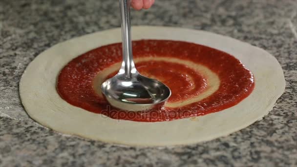 Pizza restoranında metal bir kepçeyle pizza hamuruna domates sosu sürüyor. — Stok video