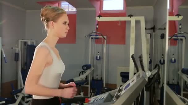 Kendi yerel spor salonunda koşu bandı üzerinde çalışan bir kız çekim — Stok video