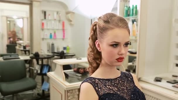 Menina em vestido de moda à noite durante a maquiagem e penteado olha no espelho — Vídeo de Stock
